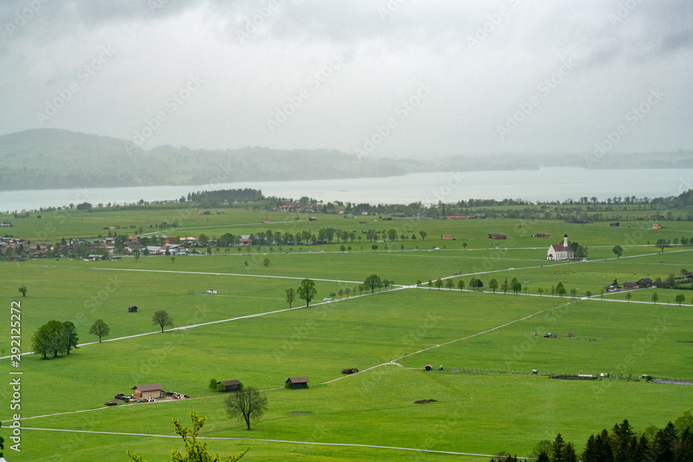 View of green meadow and lake in spring season in Schwangau from observation deck at Neuschwanstein castle. Bavaria, Germany.