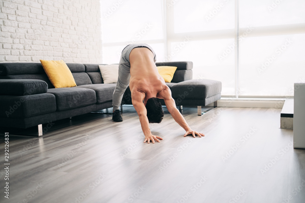 Man Practicing Yoga At Home Doing Sun Salutation Routine Man Practicing Yoga At Home Doing Sun Salutation Routine