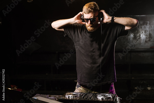 Fototapeta Naklejka Na Ścianę i Meble -  DJ plays on a mixer in the club on black background