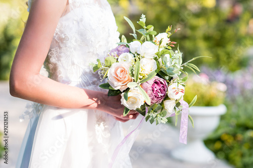Bride holding big wedding bouquet on wedding ceremony. Colorful, bright and contrast shot in sunny day.