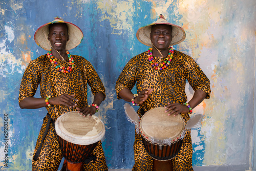 A group of people in traditional african costumes playing jembe drums