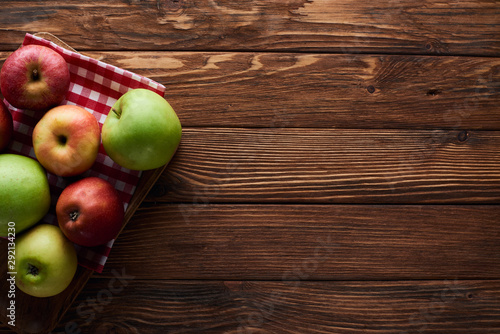 top view of checkered tablecloth with fresh apples on wooden surface with copy space photo