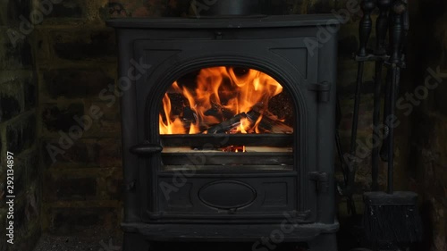4K Loaded wood burning stove with logs in, lit fire heating British home with flames