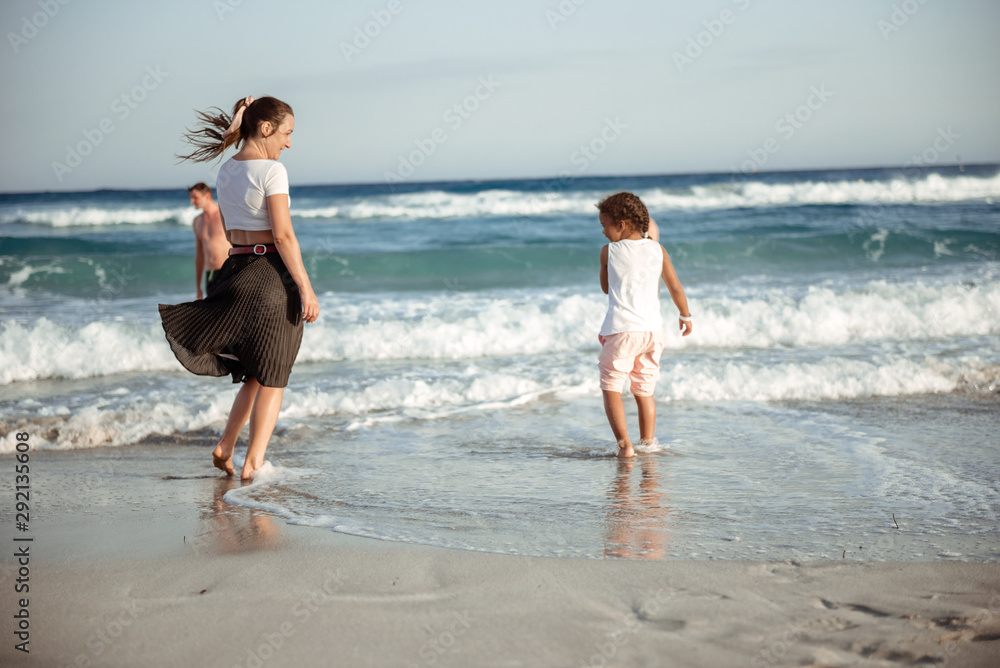 Family walking on the evening beach during sunset. Child with mom. Family walking on the evening beach during sunset. Child with mom.