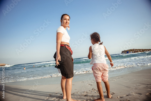 Family walking on the evening beach during sunset. Child with mom.