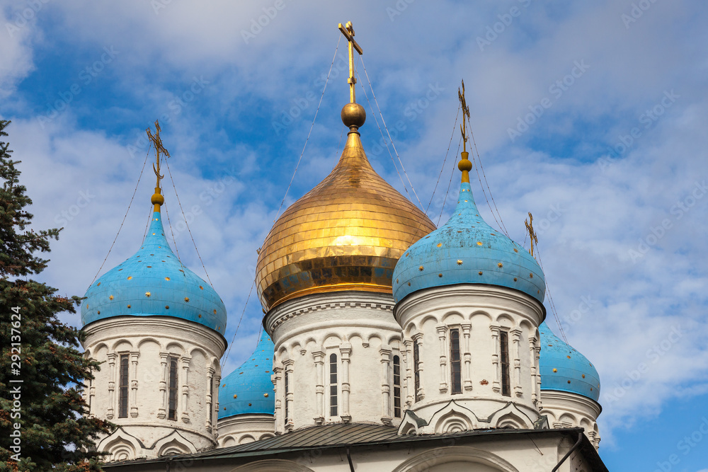 Golden and blue domes of an Orthodox church on a background of blue sky with white clouds