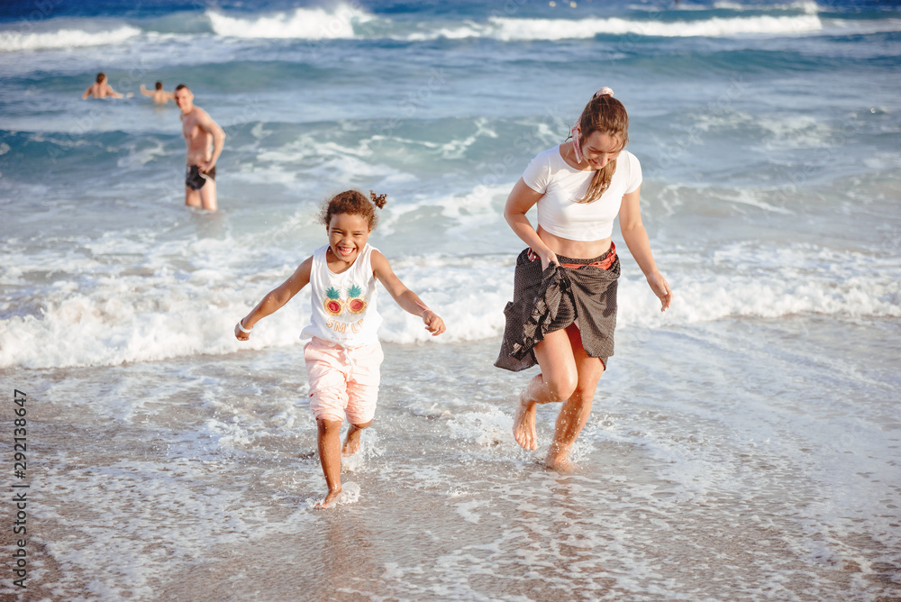 Family walking on the evening beach during sunset. Child with mom. Family walking on the evening beach during sunset. Child with mom.