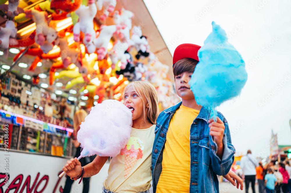 Obraz premium Boy and girl eating sweet cotton at the amusement park