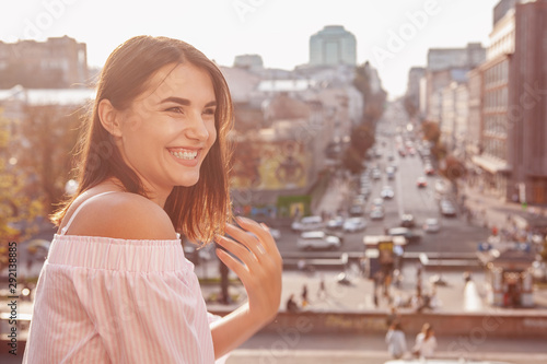 Happy healthy beautiful woman laughing joyfully wandering in city center, copy space. Gorgeous woman looking excited, laughing outdoors in the sunlight