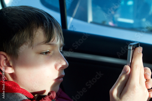 Caucasian teenage boy using smartphone in a car