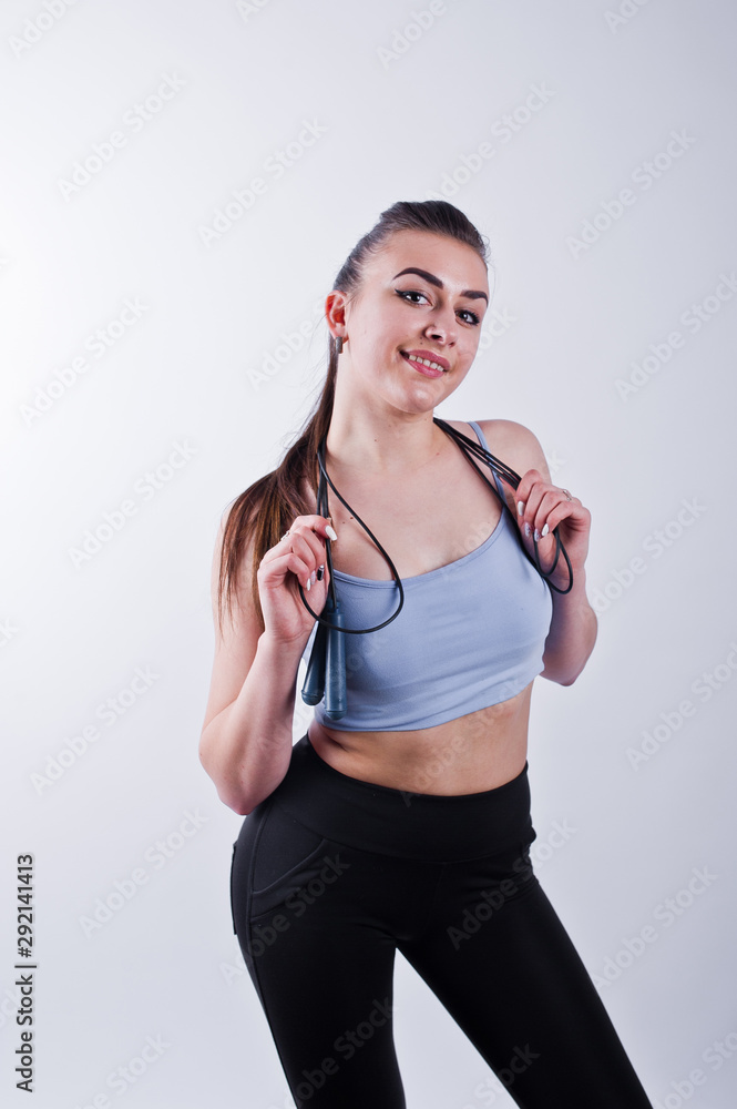 Cheerful attractive young fitness woman in top and black leggings with jump rope isolated over white background. Cheerful attractive young fitness woman in top and black leggings with jump rope isolated over white background.