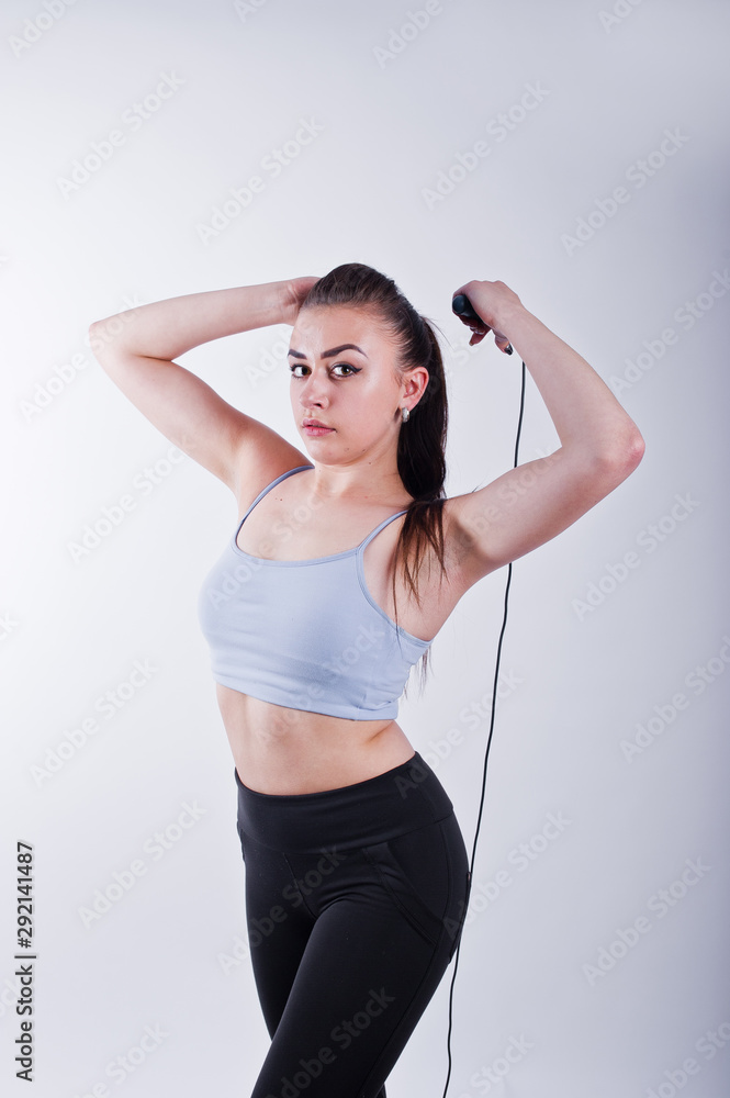 Cheerful attractive young fitness woman in top and black leggings with jump rope isolated over white background. Cheerful attractive young fitness woman in top and black leggings with jump rope isolated over white background.