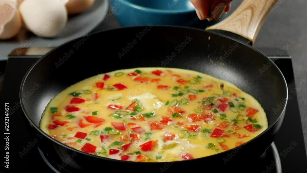 Sprinkling the omelette with pepper while frying. Slow motion. Sprinkling the omelette with pepper while frying. Slow motion.