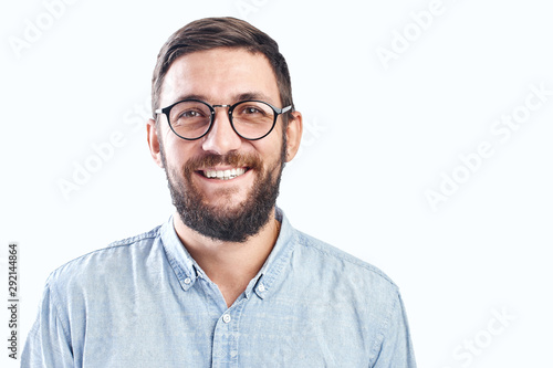 Portrait of an authentic smiling young bearded brunette man with glasses on a white background