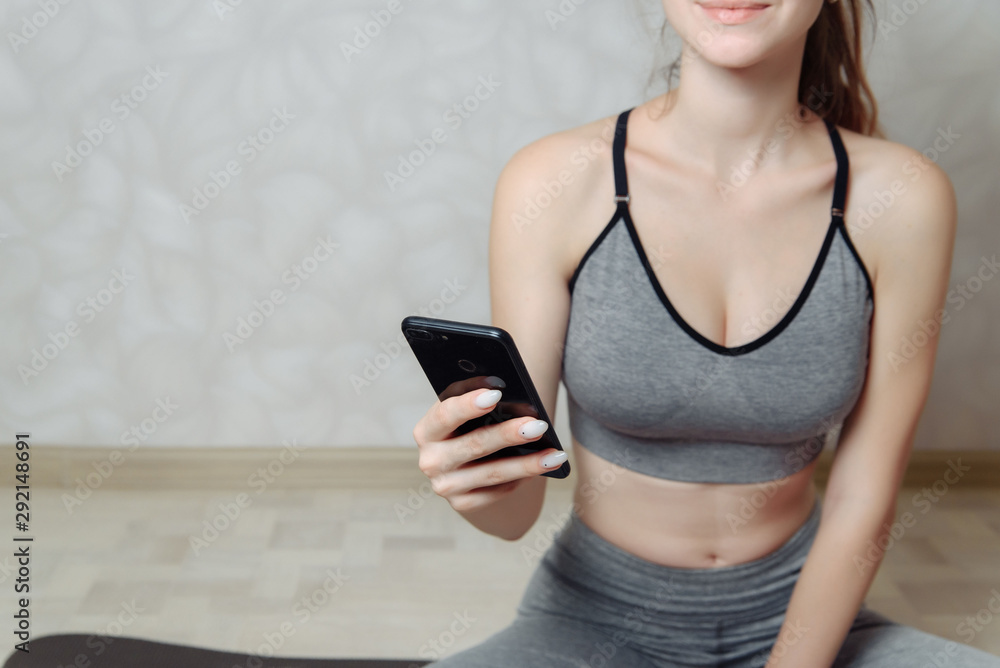 Girl has a rest after the training in the gym. Holds the smartphone in her hands. Girl has a rest after the training in the gym. Holds the smartphone in her hands.