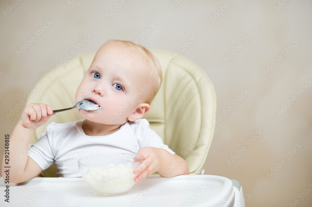 little girl licks a spoon with porridge and looks seriously at the camera little girl licks a spoon with porridge and looks seriously at the camera