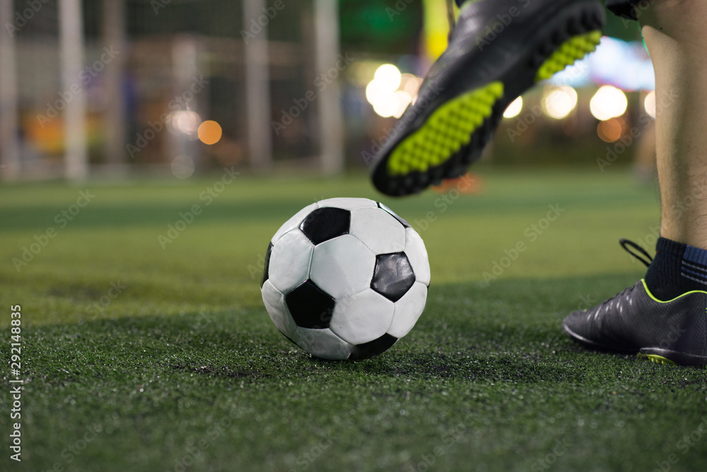 Obraz premium Soccer player foot kicking ball on football field