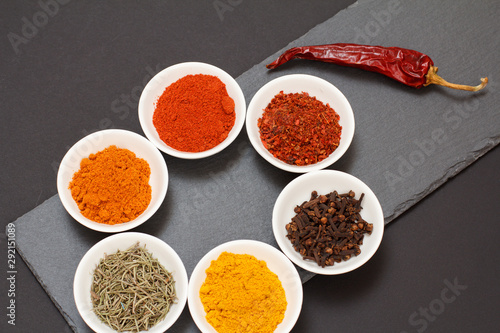 Various ground spices and herbs on stone cutting board.