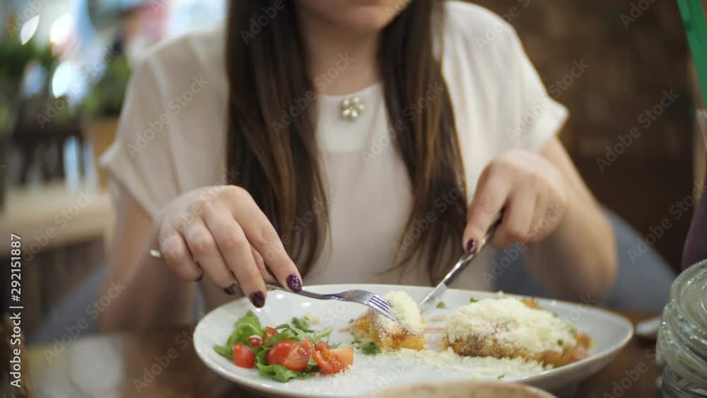 young girl eats pancakes with ham, cheese, greens and tomatoes in cafe, closeup young girl eats pancakes with ham, cheese, greens and tomatoes in cafe, closeup