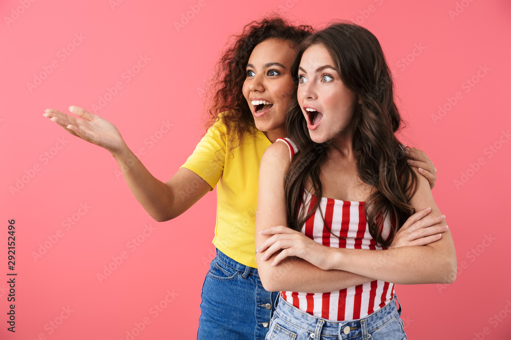 Image of excited multinational girls wondering while looking aside at copyspace Image of excited multinational girls wondering while looking aside at copyspace