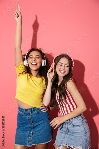 Image of optimistic multinational girls listening to music with headphones