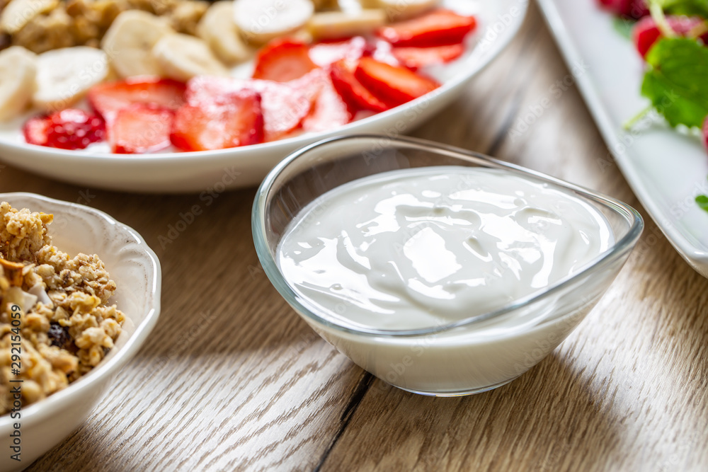 Yogurt in a glass bowl with healthy breakfast on table Yogurt in a glass bowl with healthy breakfast on table