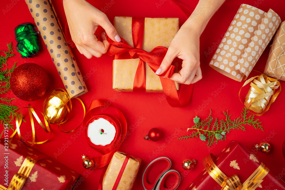 Hands of woman holding christmas gift box on a red background