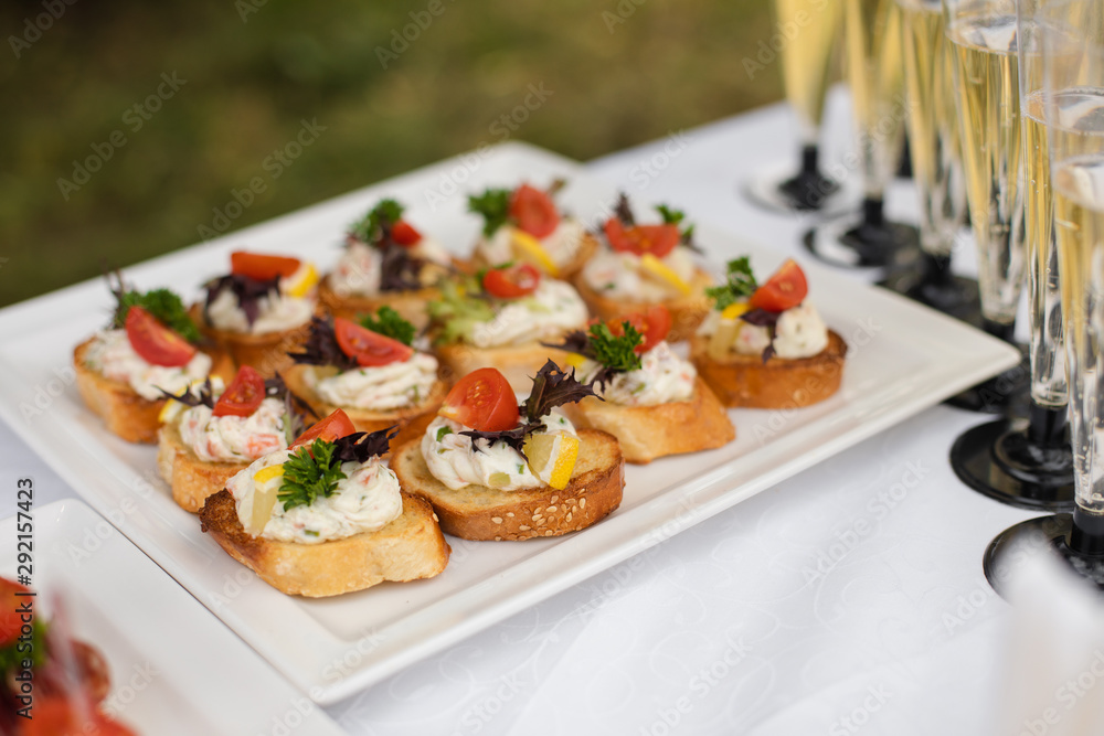 Close-up big plate with serving snack canapes fried bread tomato parsley and salami. Appetizing fresh unhealthy sandwich food decorated on table of luxury restaurant