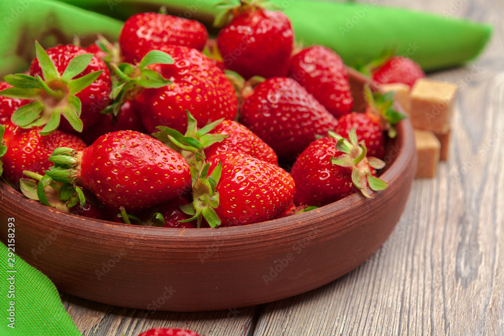 Bowl of strawberry harvest on wooden table close up Bowl of strawberry harvest on wooden table close up