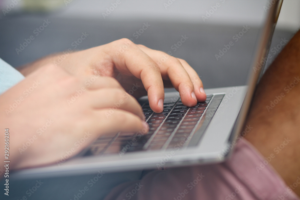 Young man typing on a laptop keyboard. Close-up details. Man's hands. Working online. Freelance concept. Shop on the couch. Online shopping. Young man typing on a laptop keyboard. Close-up details. Man's hands. Working online. Freelance concept. Shop on the couch. Online shopping.