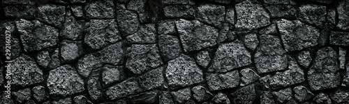 Natural granite stone wall wide texture. Dark rock masonry widescreen gloomy gothic background