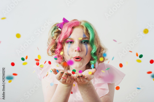 clown girl blows confetti from hands