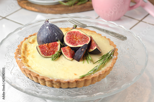 gorgeous round french classic homemade shortcake pastry dough vanilla custard tart cake decorated with figs and rosemary on glass stand near with retro fork on grey table cloth. Insta food photo style