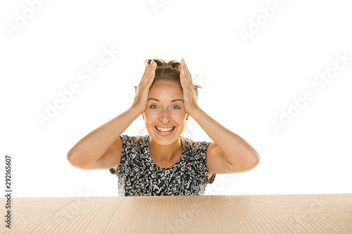 Young astonished woman opening the biggest postal package isolated on white. Shocked female model on top of cardboard box looking inside. Gift, present, delivery, shipment, sales, black friday concept