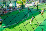 Professional football player training soccer football in blurred background behind the net.