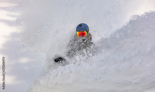 female snowboarder curved and brakes spraying loose deep snow on the freeride slope. downhill with snowboards in fresh snow. freeride world champion.