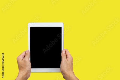 Male hands holding a tablet touch computer gadget with yellow background,copy space.