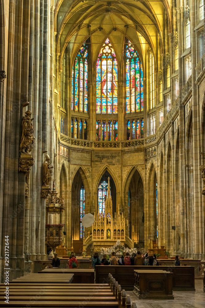 Fototapeta premium Tourists inside Vitus Cathedral near the altar with mosaic on glass window