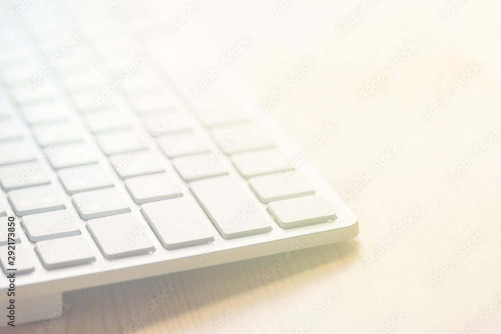 White computer keyboard on wood tabletop. Blurred abstract background for business studying freelance self-employment concept copywriter's workplace