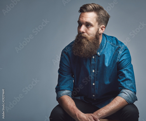 Fotografi Young man sitting pensively against a gray background