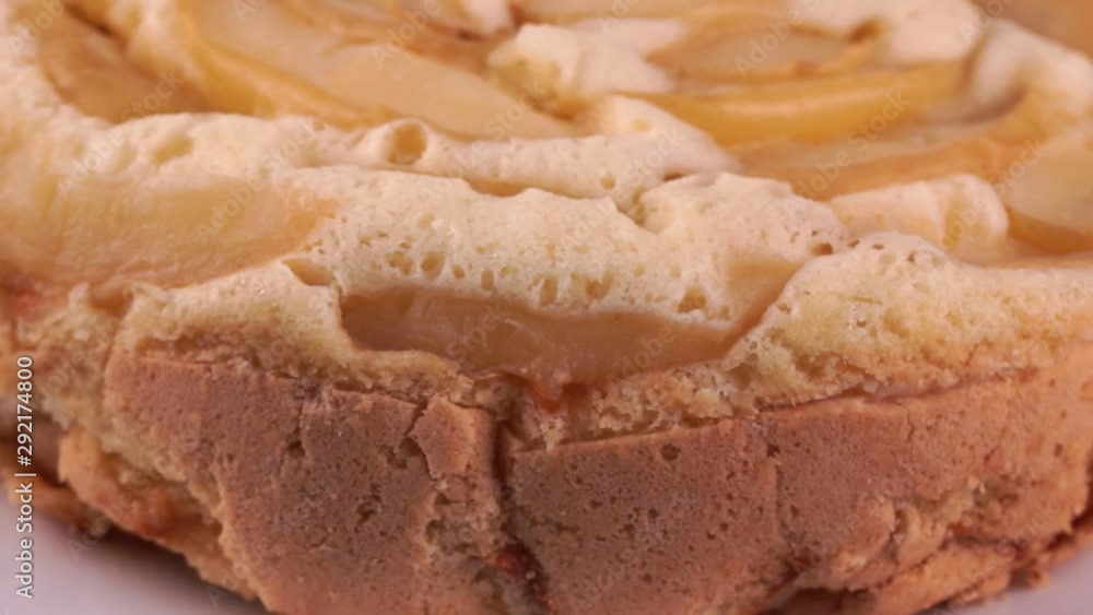 Baked apple pie on a white plate rotates in a closeup frame on a brown wooden background Baked apple pie on a white plate rotates in a closeup frame on a brown wooden background