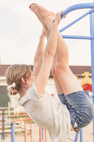 Young woman is exercising on horizontal bar outdoors