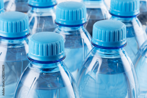 Rows of plastic bottles. Necks of plastic bottles with still mineral water with blue caps, close up