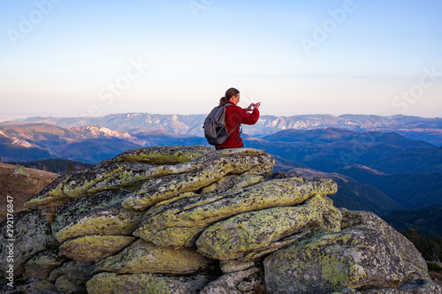 male hiker standing on rock formations taking photos