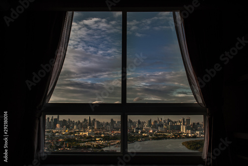 The beautiful view of Bangkok, the beautiful skyscrapers along the Chao Phraya River in the evening seen through a bedroom window.