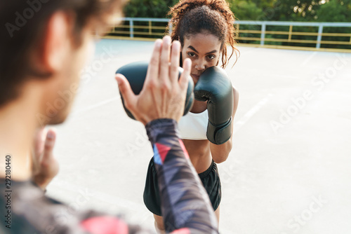 Photo of multinational focused couple working out in boxing gloves