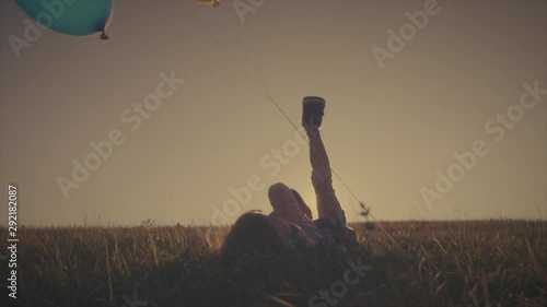 Vintage video of a llittle girl playing with some balloons on a meadow photo