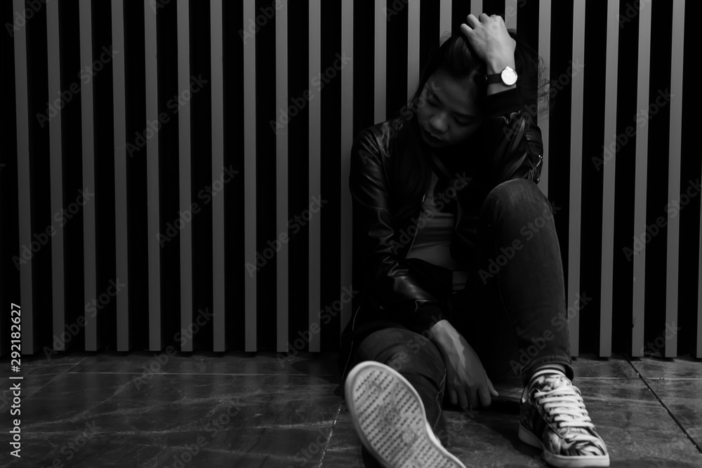 Portrait of asian girl are sitting on the floor beside the wall and looked sad. Black and white images of Thai women are suffering from depression. Portrait of asian girl are sitting on the floor beside the wall and looked sad. Black and white images of Thai women are suffering from depression.