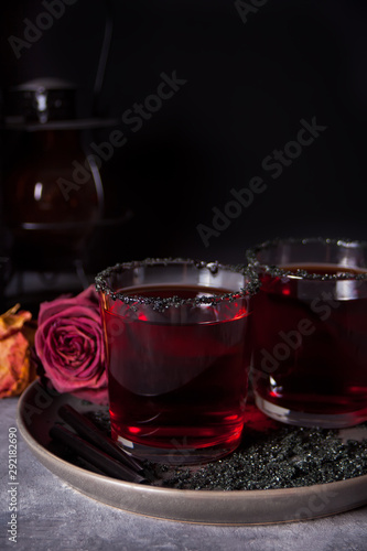 Two glasses with red cocktail, dried roses for Halloween party on the dark background