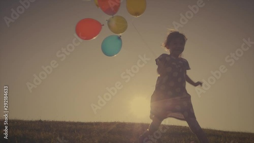 Retro home retro video of a little girl playing and falling down with some balloons, filmed in slow motion photo
